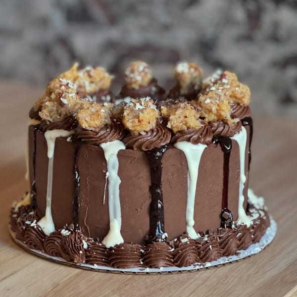 A chocolate cake with white and dark chocolate drizzle, topped with chocolate frosting and macaroons.