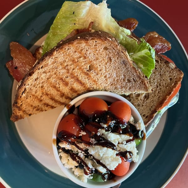 Jamie’s Eats and Sweets' bacon, lettuce, and tomato sandwich with a side of tomato and feta salad.