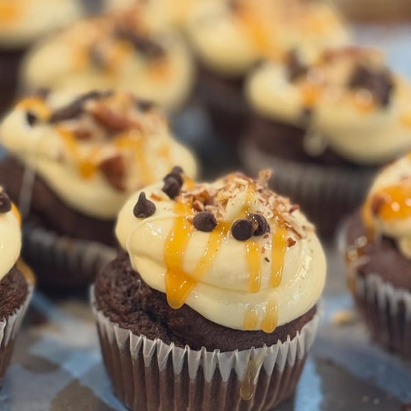 Chocolate cupcakes with vanilla frosting, caramel drizzle, chocolate chips, and nuts at Jamie's Eats and Sweets.